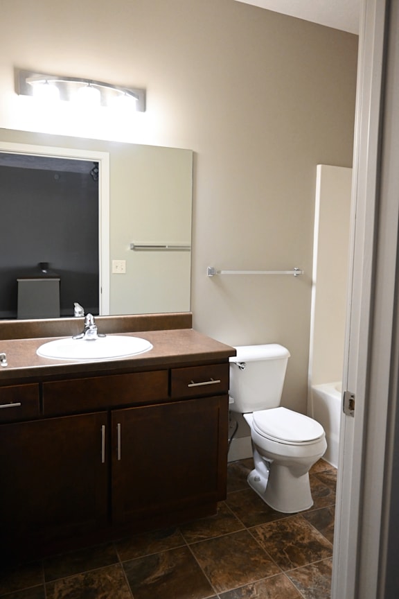 A bathroom with a toilet, sink, and mirror.