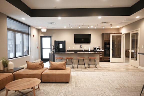 A modern living room with a kitchen area in the background.