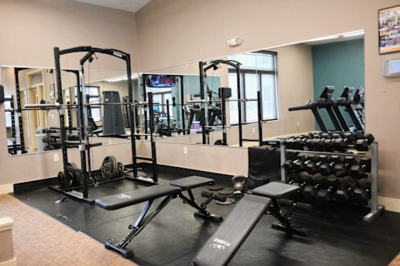 A gym with a variety of equipment including weights and weight machines.