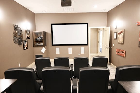 A home theater with a large screen and black chairs.