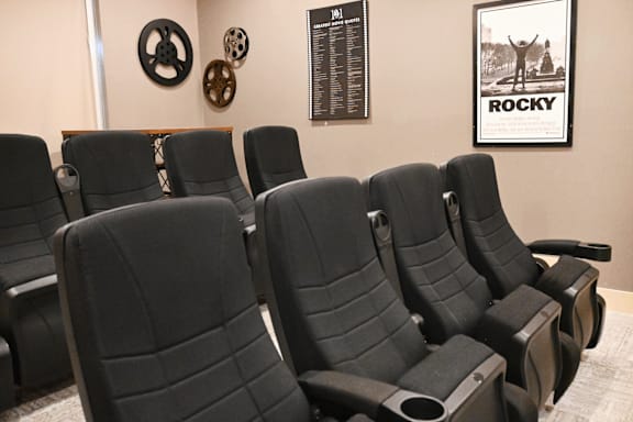 A row of black theater seats with a poster of a man on the wall.
