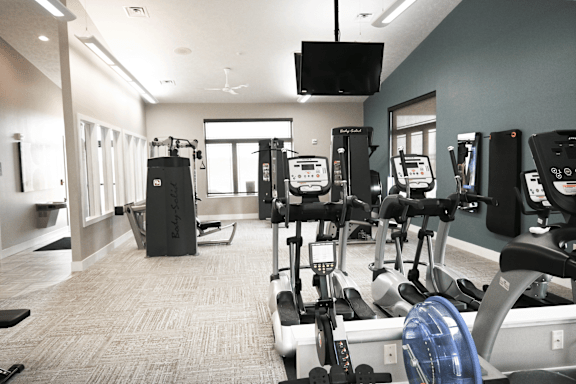 A gym with a variety of exercise equipment including treadmills, stationary bikes, and weight machines.