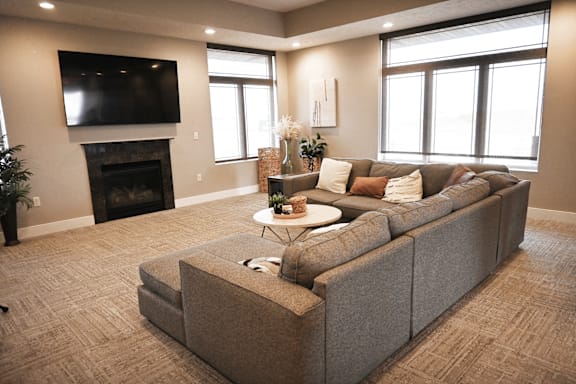 A large grey couch in a living room with a flat screen TV mounted on the wall above it.