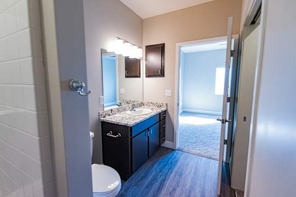 Bathroom with vanity, sink, mirror, toilet and vinyl flooring at Heartland Flats Alliance.