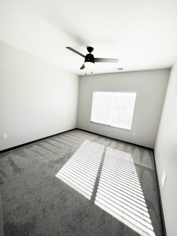A room with a ceiling fan and a window with blinds.