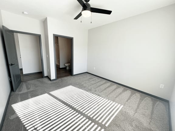 A room with a ceiling fan and a striped rug on the floor.