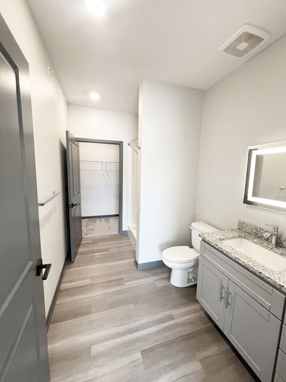 A bathroom with a toilet, sink, and mirror.