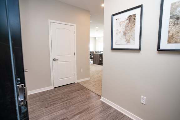 A hallway with a white door and two framed pictures on the wall.