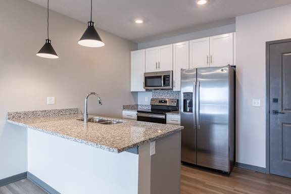 Kitchen with white cabinetry stainless steel appliances and island seating at The Harbor