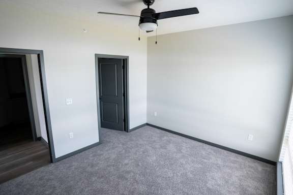 Bedroom with carpet flooring ceiling fan and a door at The Harbor