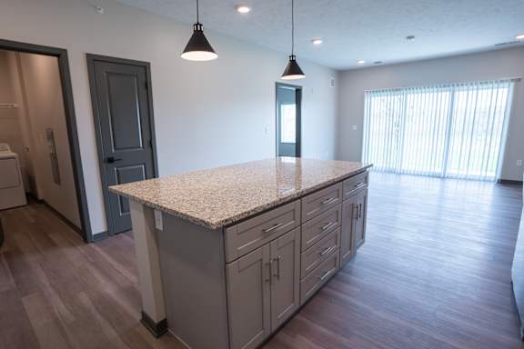 Kitchen island with cabinets pendant lights and open space around it at The Harbor