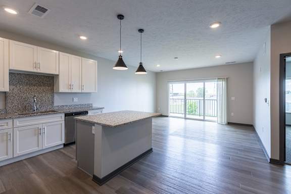 Kitchen with island and pendant lighting facing a sliding glass door to outdoor space at The Harbor.