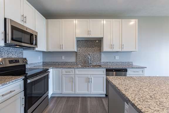 Stainless steel stove, microwave and white cabinetry in a bright kitchen at The Harbor.
