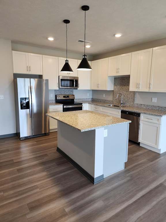 Kitchen with island, pendant lighting and a sliding door leading to outdoor space at The Harbor.