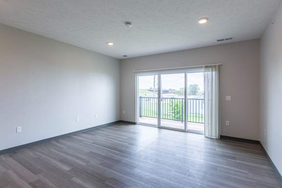 Open living room with wood style floors and sliding glass door leading outside at The Harbor.