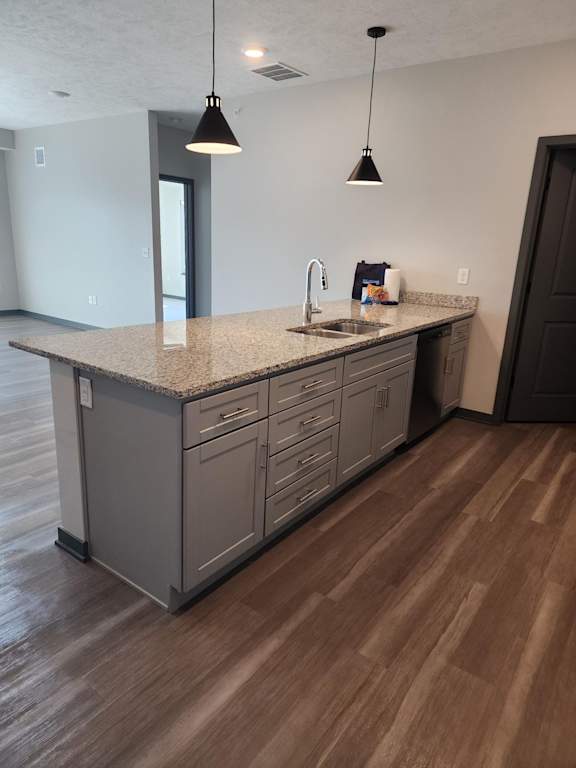 Kitchen island with light cabinets, pendant lights and wood style flooring at The Harbor.