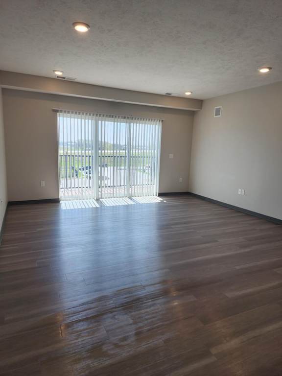Living room with wood style flooring and large sliding door leading to outdoor space at The Harbor.