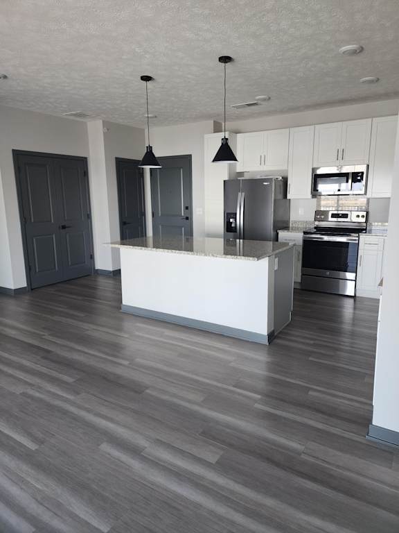 Kitchen with stainless steel appliances and island facing the entry and hallway at The Harbor.