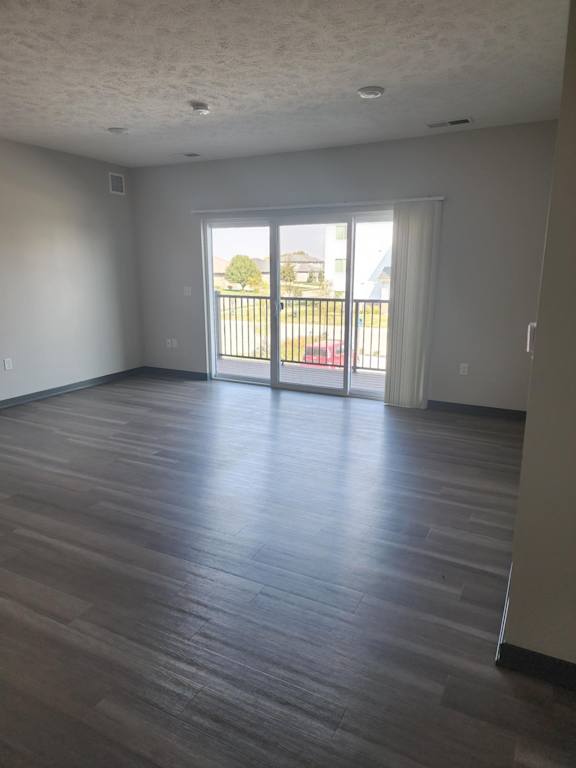 Living room with wood style flooring and sliding glass doors leading to an outdoor area at The Harbor.
