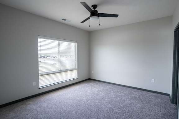 Bedroom with carpet, ceiling fan and window on exterior wall at The Harbor.