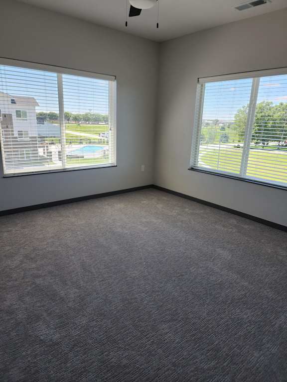 Bedroom with carpet flooring and multiple windows providing natural light at The Harbor.