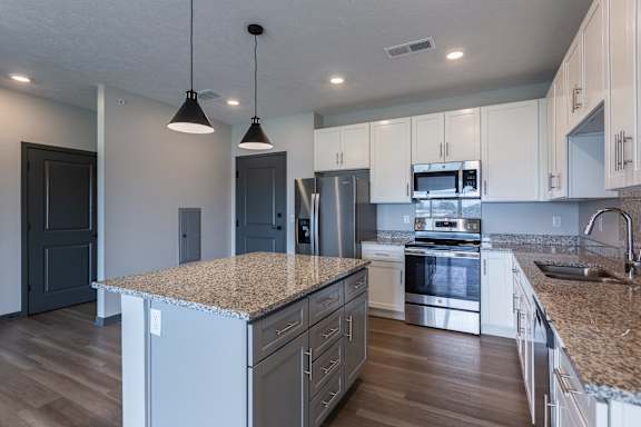 Close view of the kitchen island with pendant lighting and stainless appliances at The Harbor.