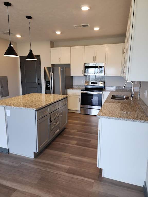 Kitchen with island facing an open dining or living space with sliding door access at The Harbor.
