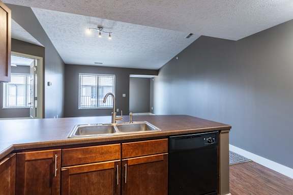 A carpeted living room with a view into the kitchen in the Durham home at The Sterling at Grand Island.