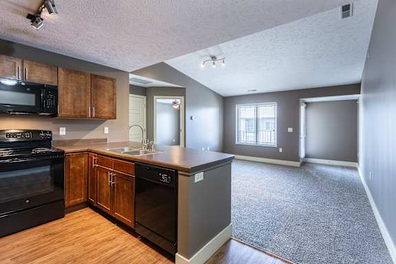 A kitchen with wood cabinets and adjacent living space in the Durham home at The Sterling at Grand Island.