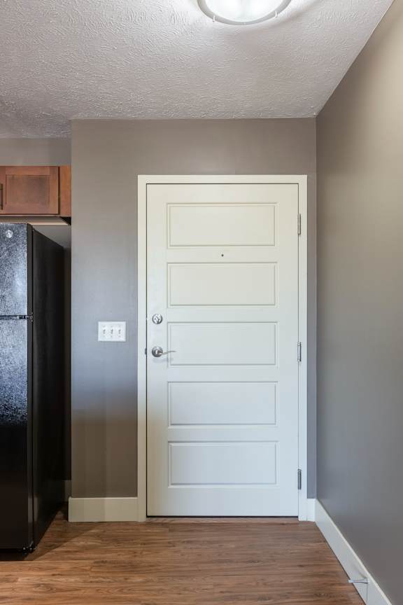 A carpeted living area with a view toward the entry and kitchen in the Kingston Garden Level home at The Sterling at Grand Island.