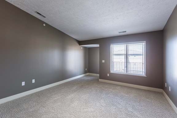 A carpeted bedroom with a ceiling fan and closet access in the Kingston Garden Level home at The Sterling at Grand Island.