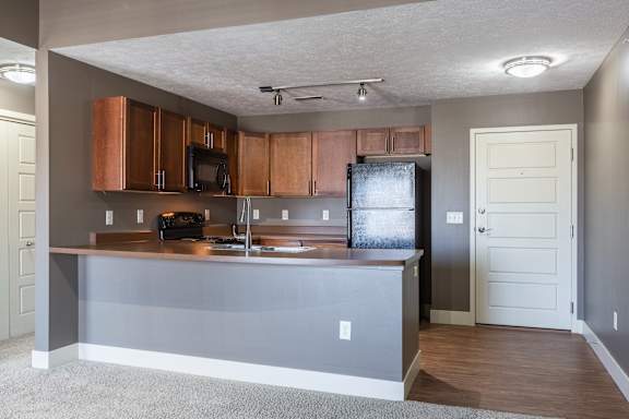 A view of the kitchen and carpeted living space in the Manchester ADA home at The Sterling at Grand Island.