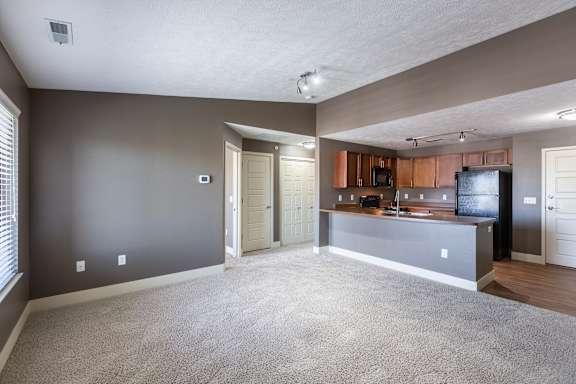 A carpeted bedroom with a window allowing natural light in the Manchester ADA home at The Sterling at Grand Island.