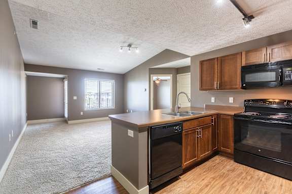 A kitchen with wood cabinetry and adjacent dining space in the Manchester ADA home at The Sterling at Grand Island.