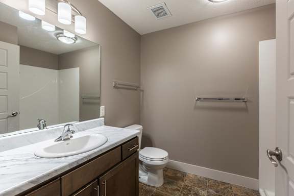 Bathroom with a wide vanity a sink and overhead lighting