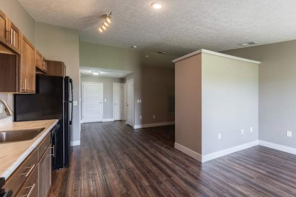 Open living area with wood flooring and a view of the kitchen and hallway
