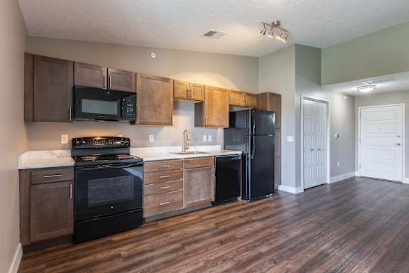 Kitchen with wood cabinets black appliances and wood flooring