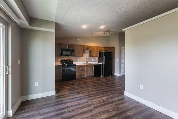 Kitchen area with overhead lighting and wood flooring seen from the entry