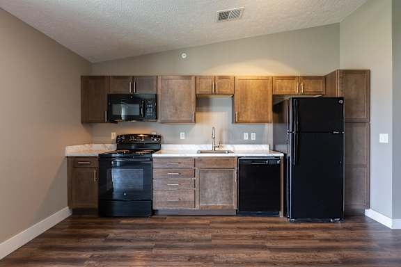 Kitchen with wood cabinets black appliances and wood flooring
