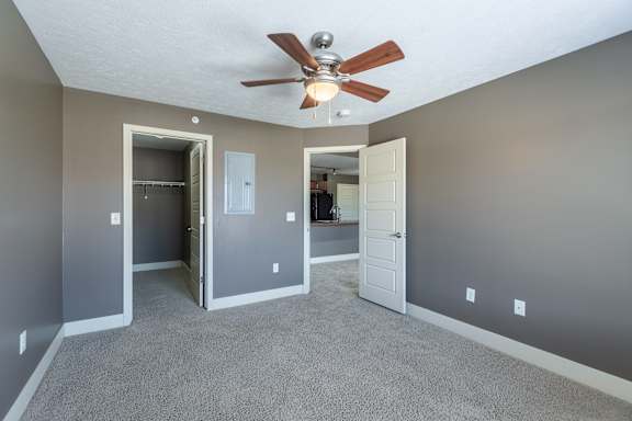 A bedroom with a ceiling fan and a closet door in the Manchester home at The Sterling at Grand Island.