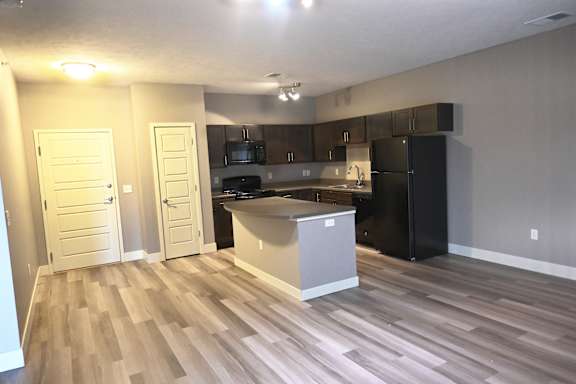 Kitchen with island facing the living area with wood style flooring at The Sterling at Kearney
