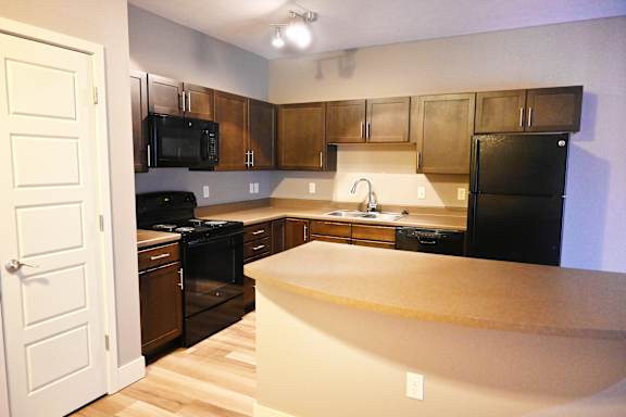 Kitchen with wood cabinets black appliances and peninsula counter at The Sterling at Kearney