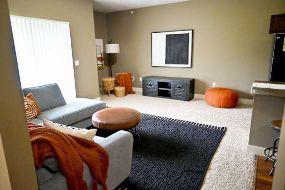 Living room with sofa chair and mounted television at The Sterling at Kearney