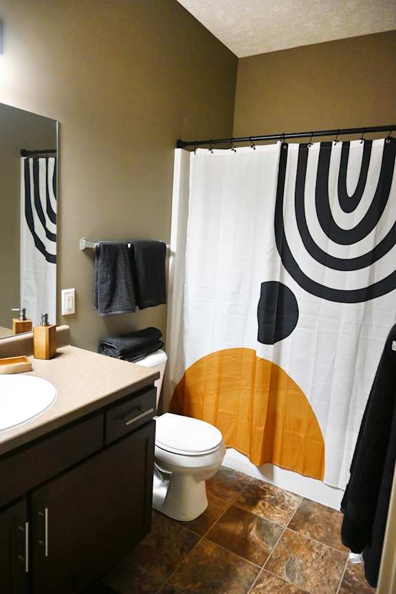Bathroom with patterned shower curtain and toilet at The Sterling at Kearney