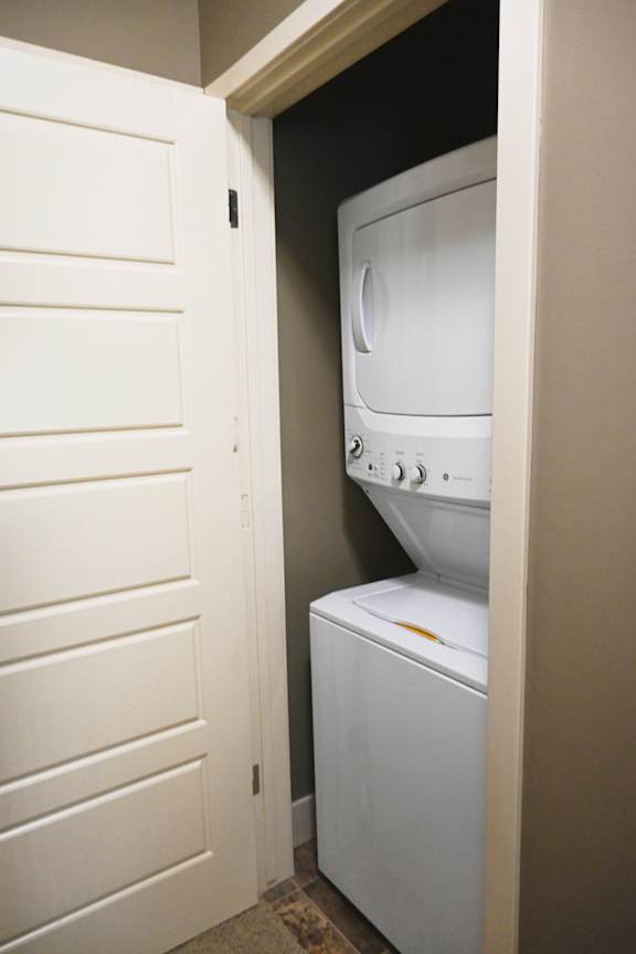 Stacked washer and dryer in a closet with white doors at The Sterling at Kearney