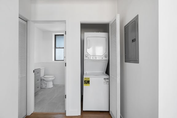 a white bathroom with a washer and dryer and a door to a white