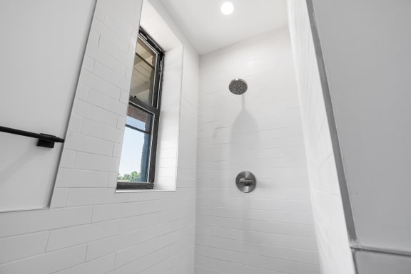 a white bathroom with a shower and a window