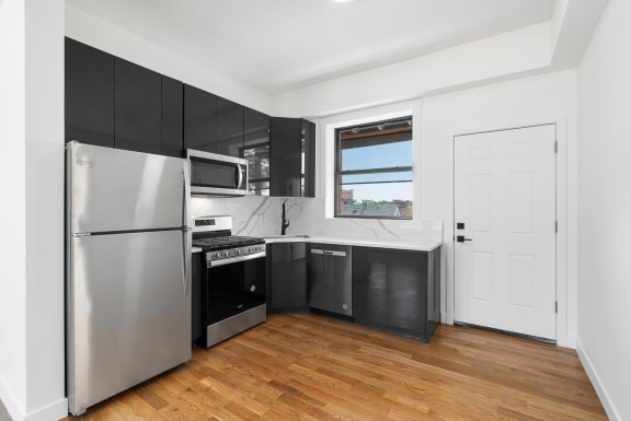 a kitchen with black cabinets and stainless steel appliances and a window