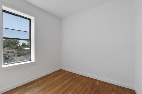 a room with white walls and a window and wooden floors