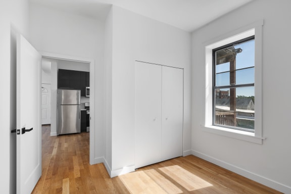 a living room with white walls and a window and wooden floors